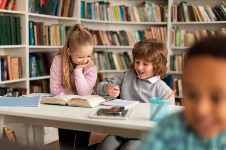 School children sitting in library, reading book and doing homework, chatting or preparing school